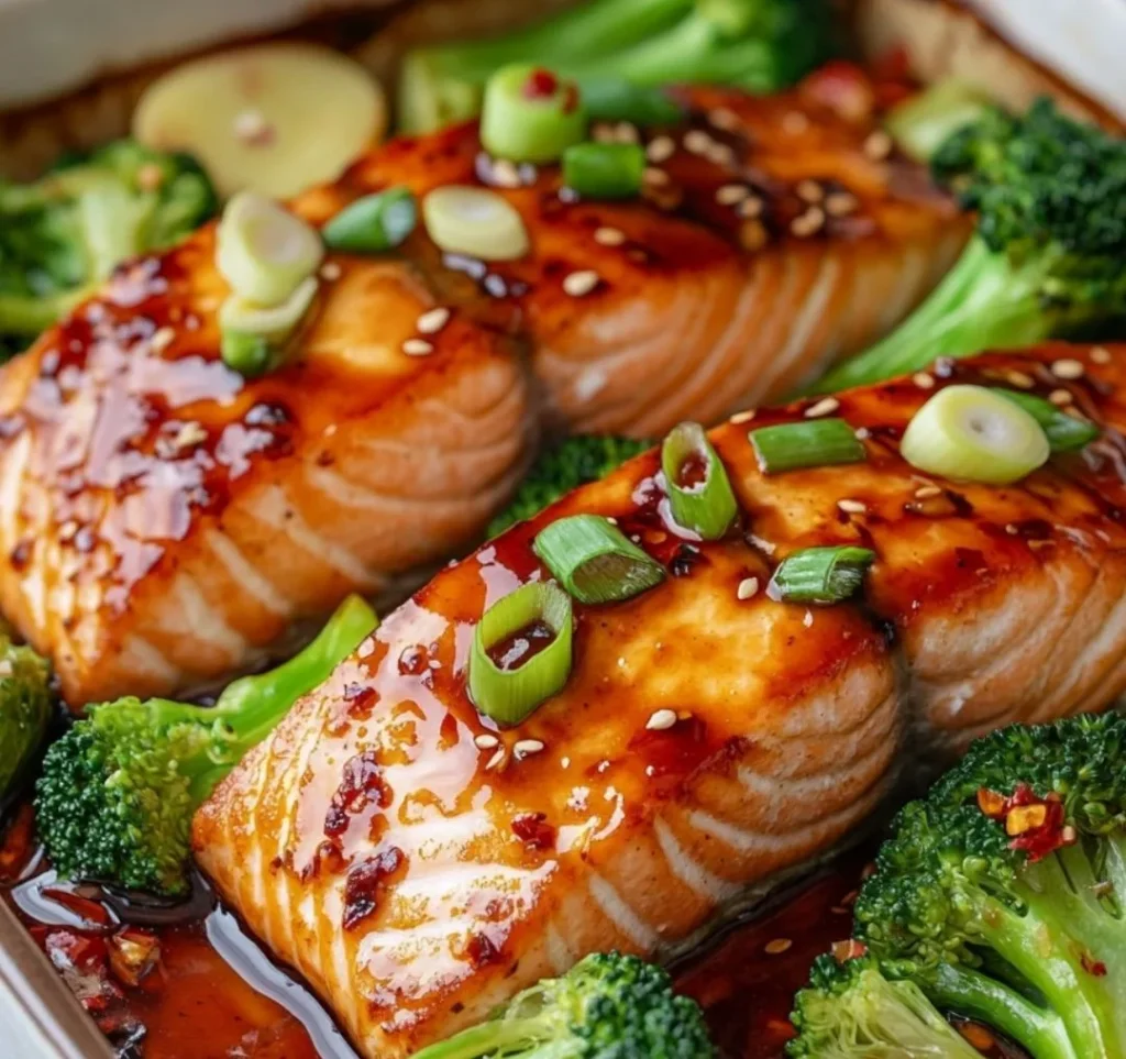ugnsbakad lax med teriyakisås, inklusive laxfiléer, broccoli och sojasås, på en träbänk i ett ljust kök.